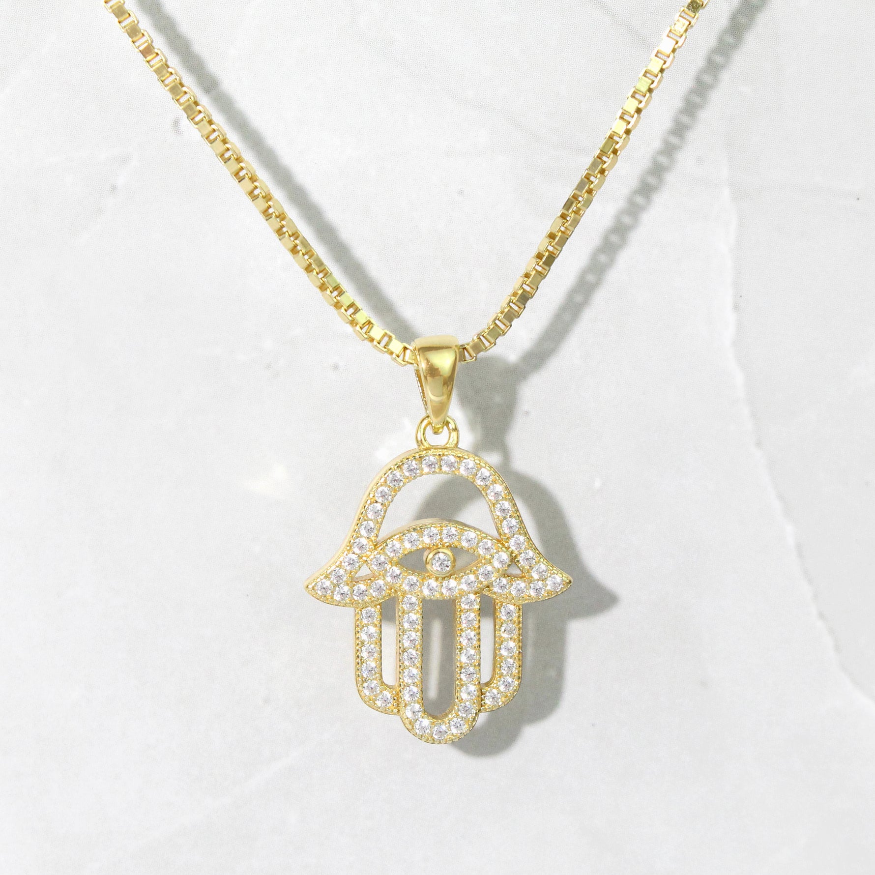 Upclose shot of gold hamsa necklace. 