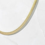 Upclose shot of a gold minimalist herringbone chain necklace.