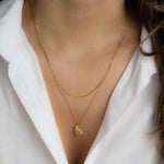 Model wearing minimalist gold thin chain necklace with an oval medallion gold pendant necklace. 