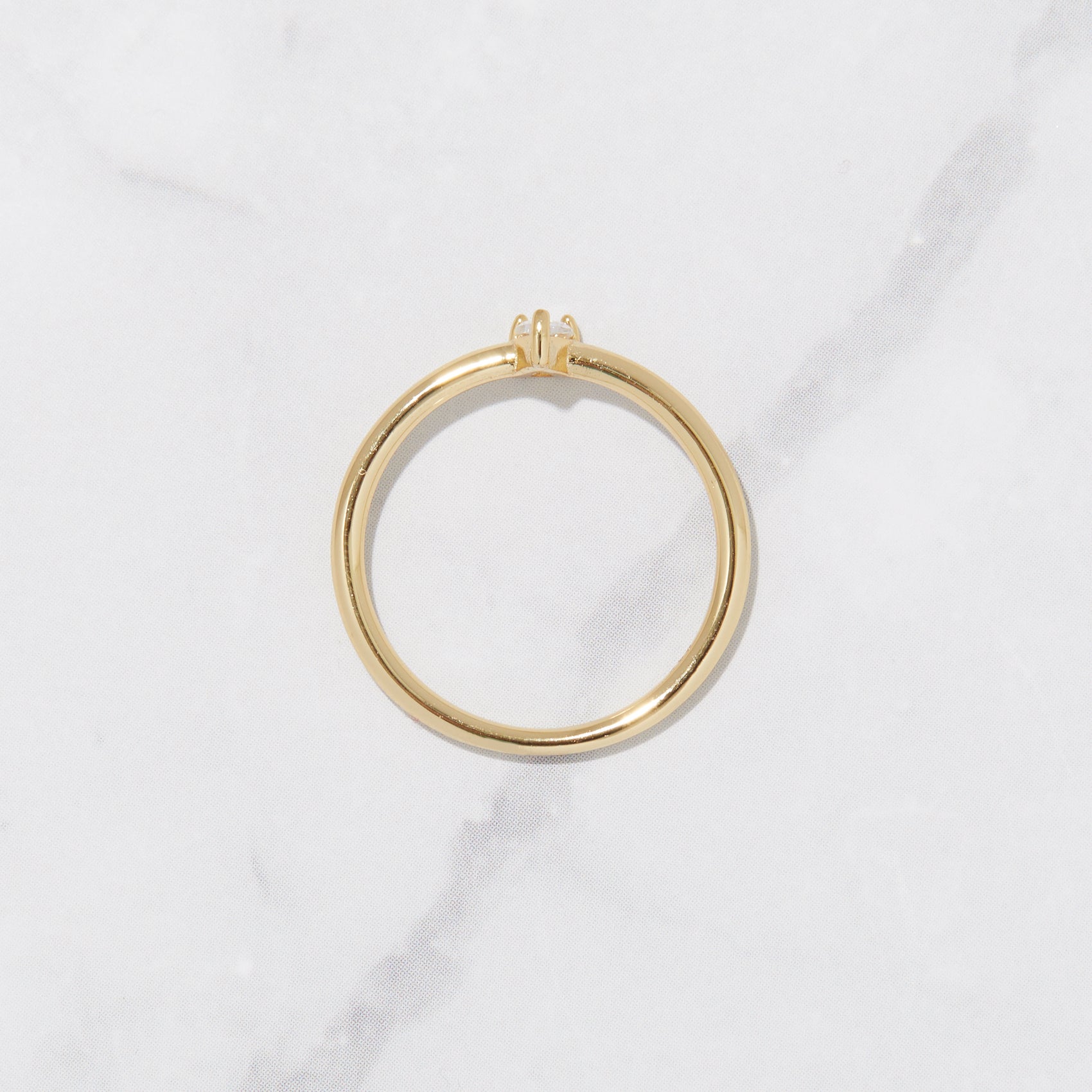 Dainty gold pear stone ring in gold on marble background. 