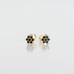 Upclose shot of gold dainty flower stud earrings in black. 
