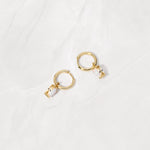 Gold opal charm huggie earrings from the side angle. 