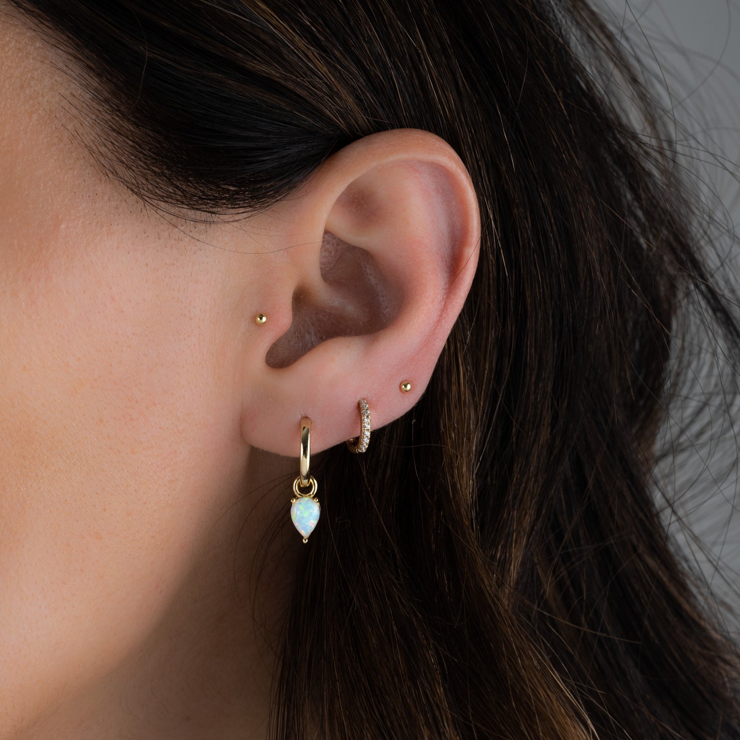 Gold dainty opal charm earring stack on model. 