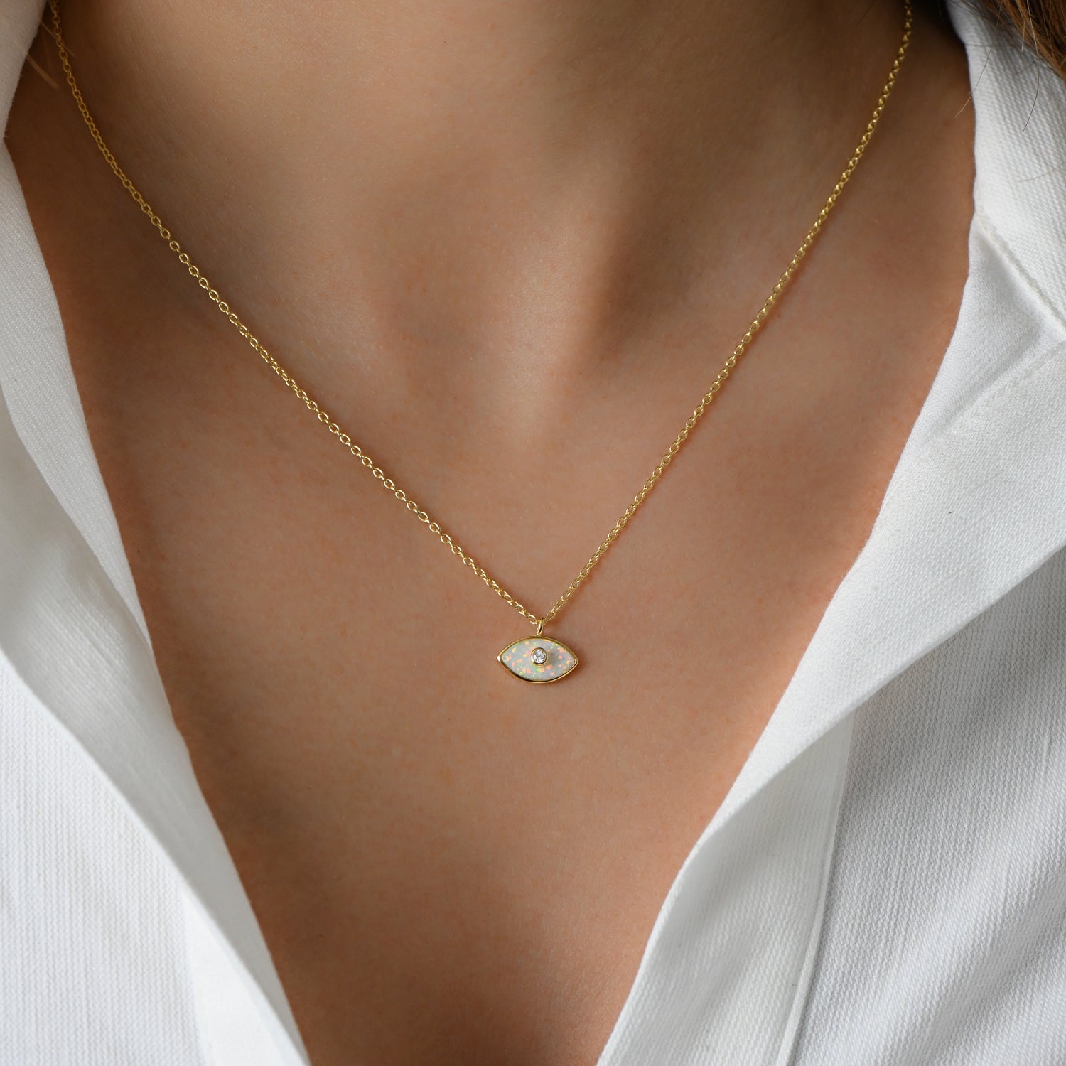 Model wearing delicate gold chain with opal evil eye necklace.