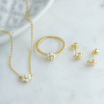 Opal flower gold jewelry set featuring a chain necklace, a opal flower ring, and opal flower stud earrings on a marble background.