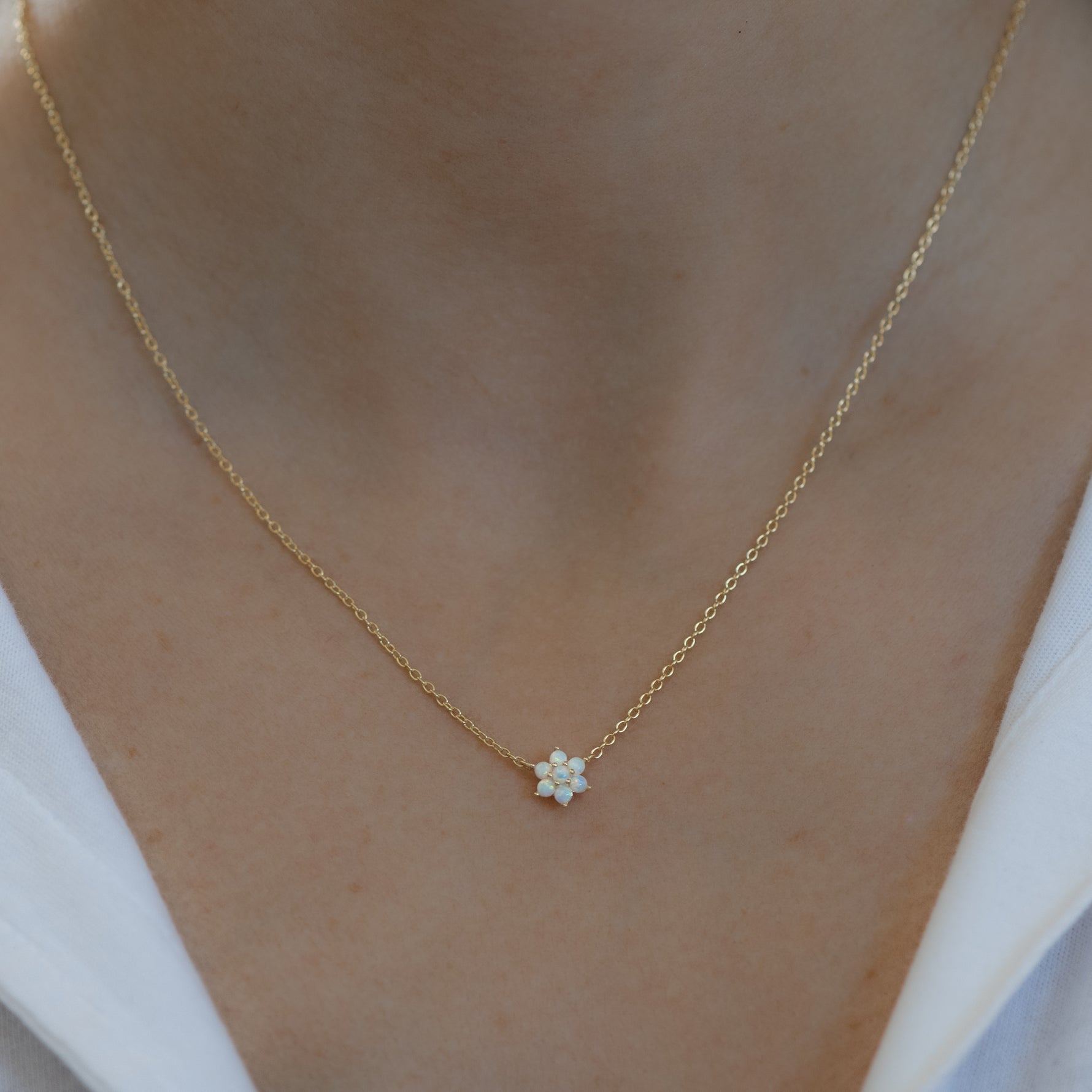 Model wearing delicate gold opal flower necklace. 