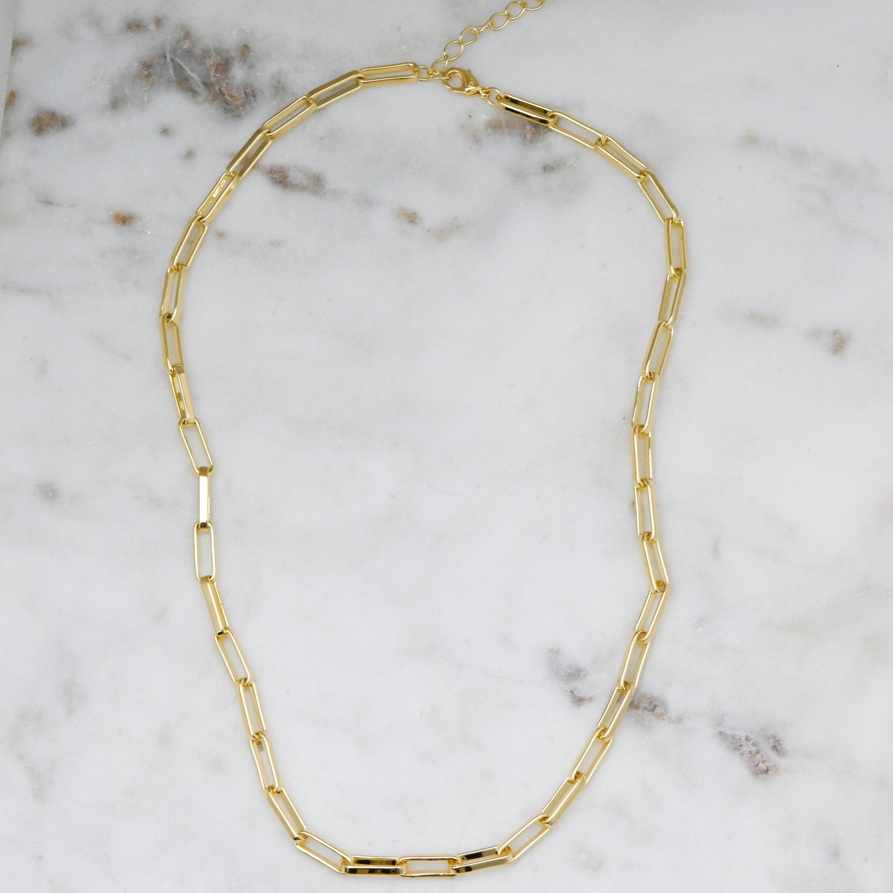 Gold 14K plated paperclip chain on a marble background. 