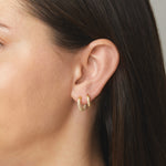 Model wearing diamond studded gold hoop earrings. 