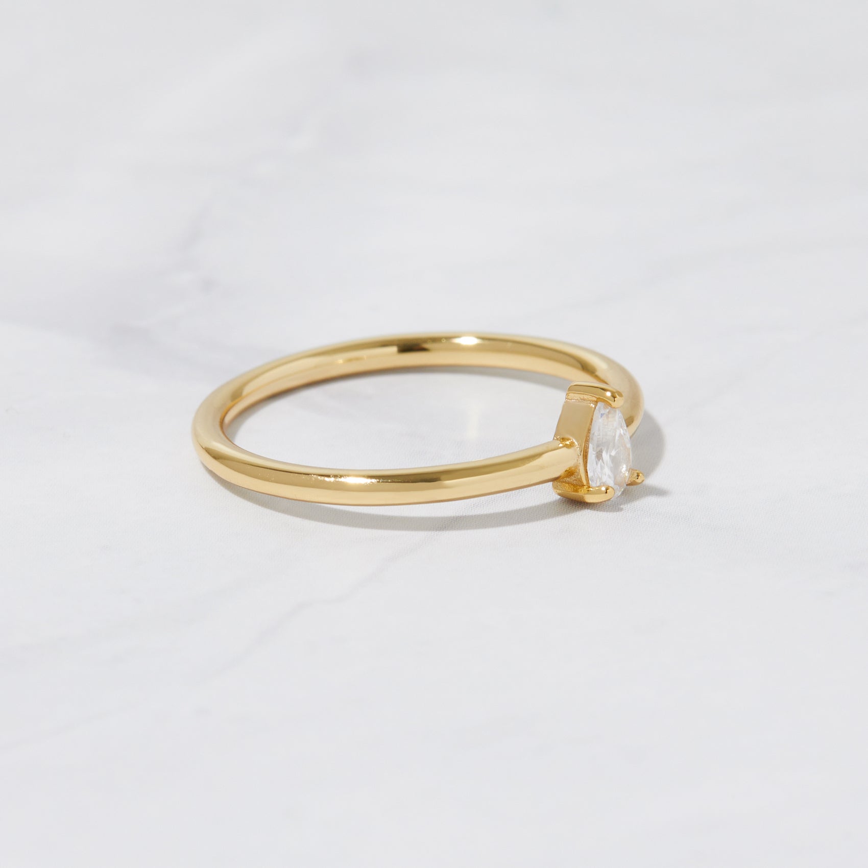 Dainty gold stacking ring on marble background. 