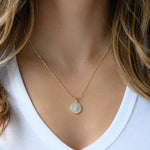 Model wearing mother of pearl circle pendant necklace. 