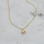 Delicate gold evil eye protection necklace on marble background