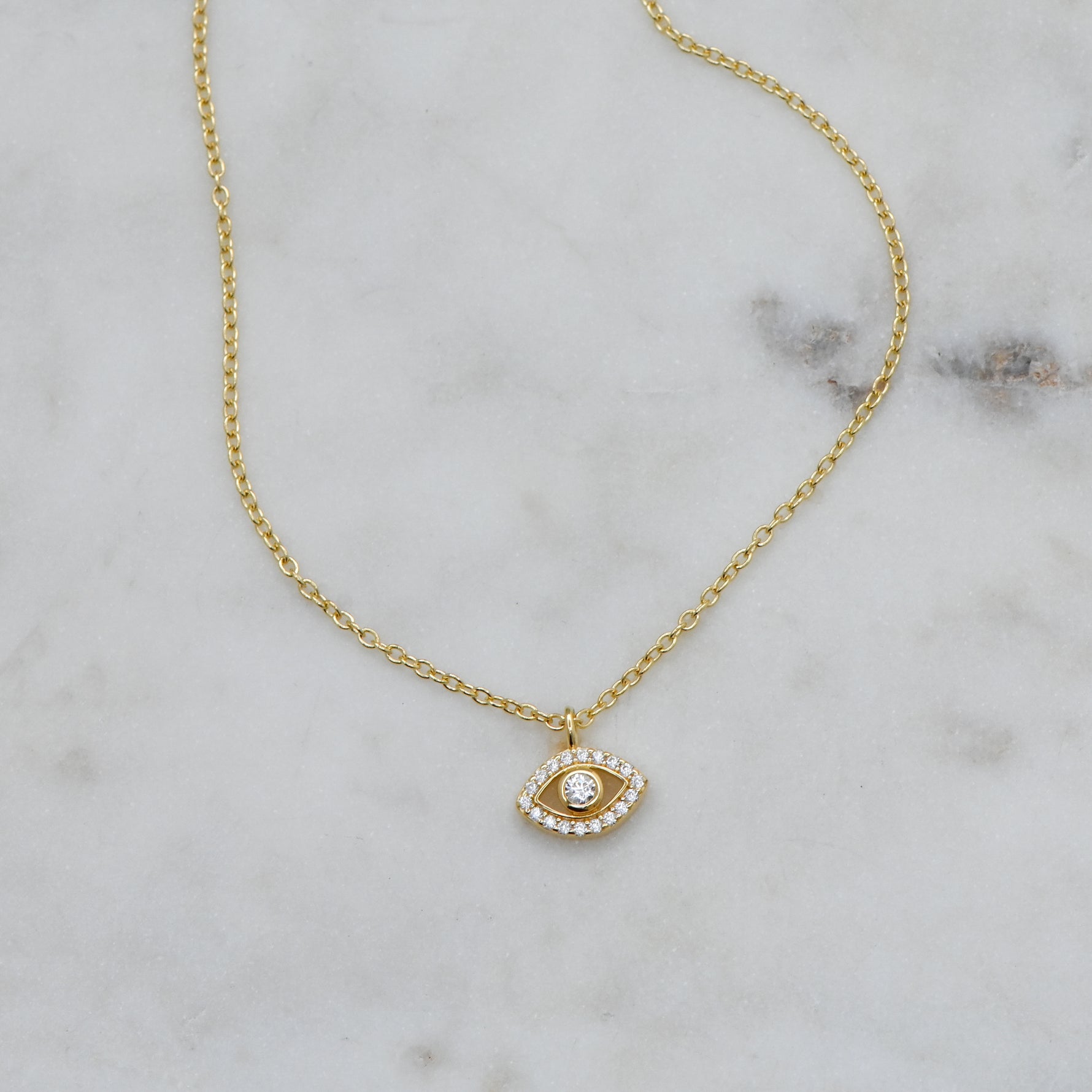 Delicate gold evil eye protection necklace on marble background