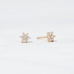 Close up image of rose-gold diamond flower stud earrings. 