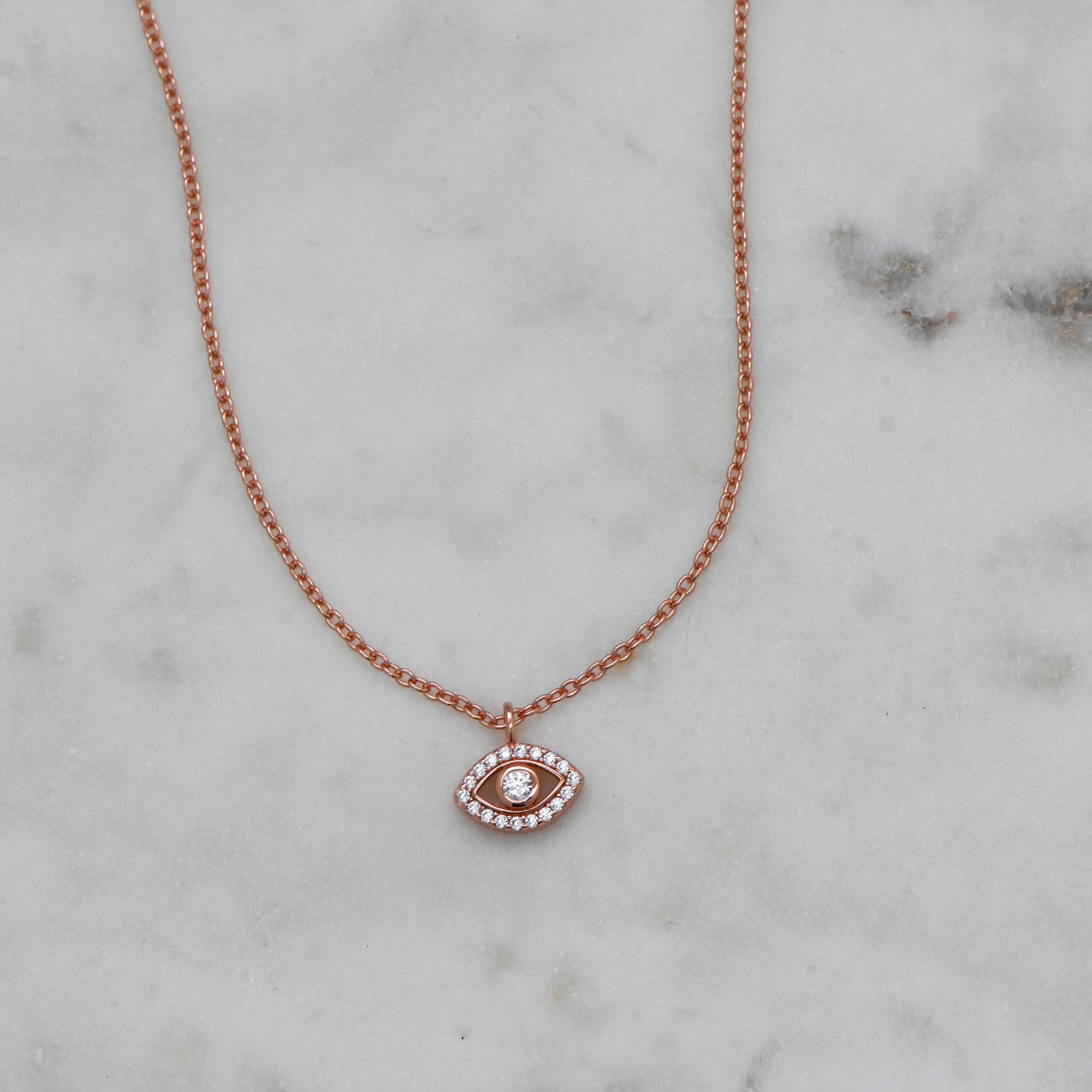 Delicate rose gold evil eye protection necklace on marble background