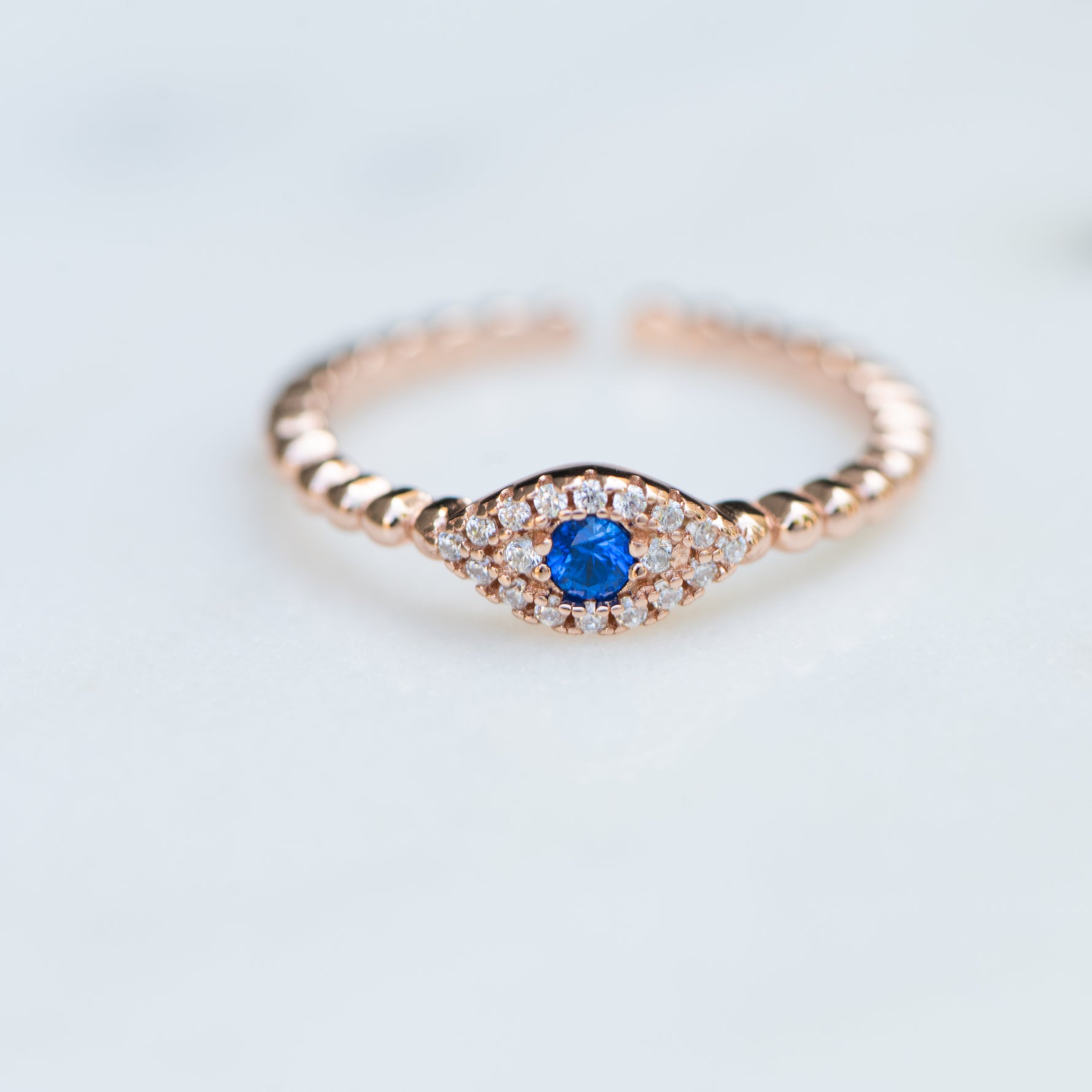 Dainty rose gold beaded evil eye ring with sapphire gemstone center. 