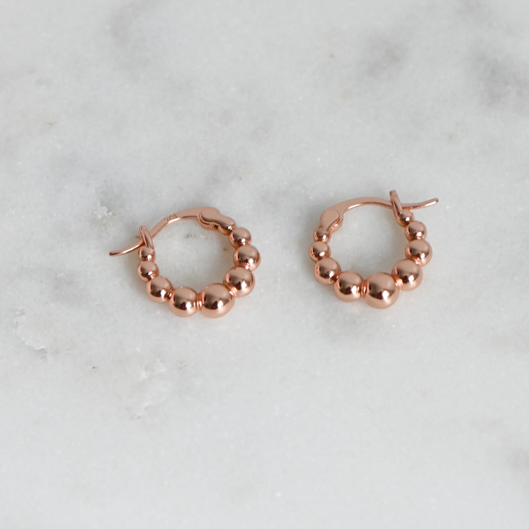 Rose gold beaded gradient hoop earrings.