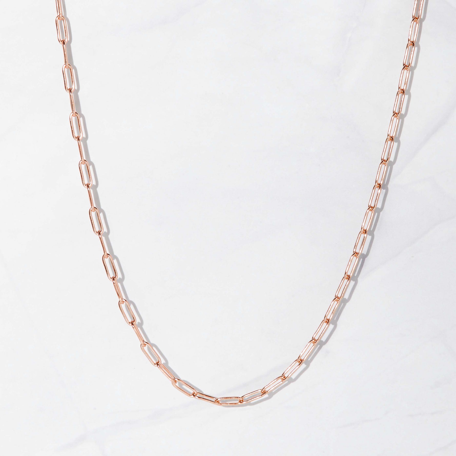 Delicate rose gold paperclip chain necklace on marble background
