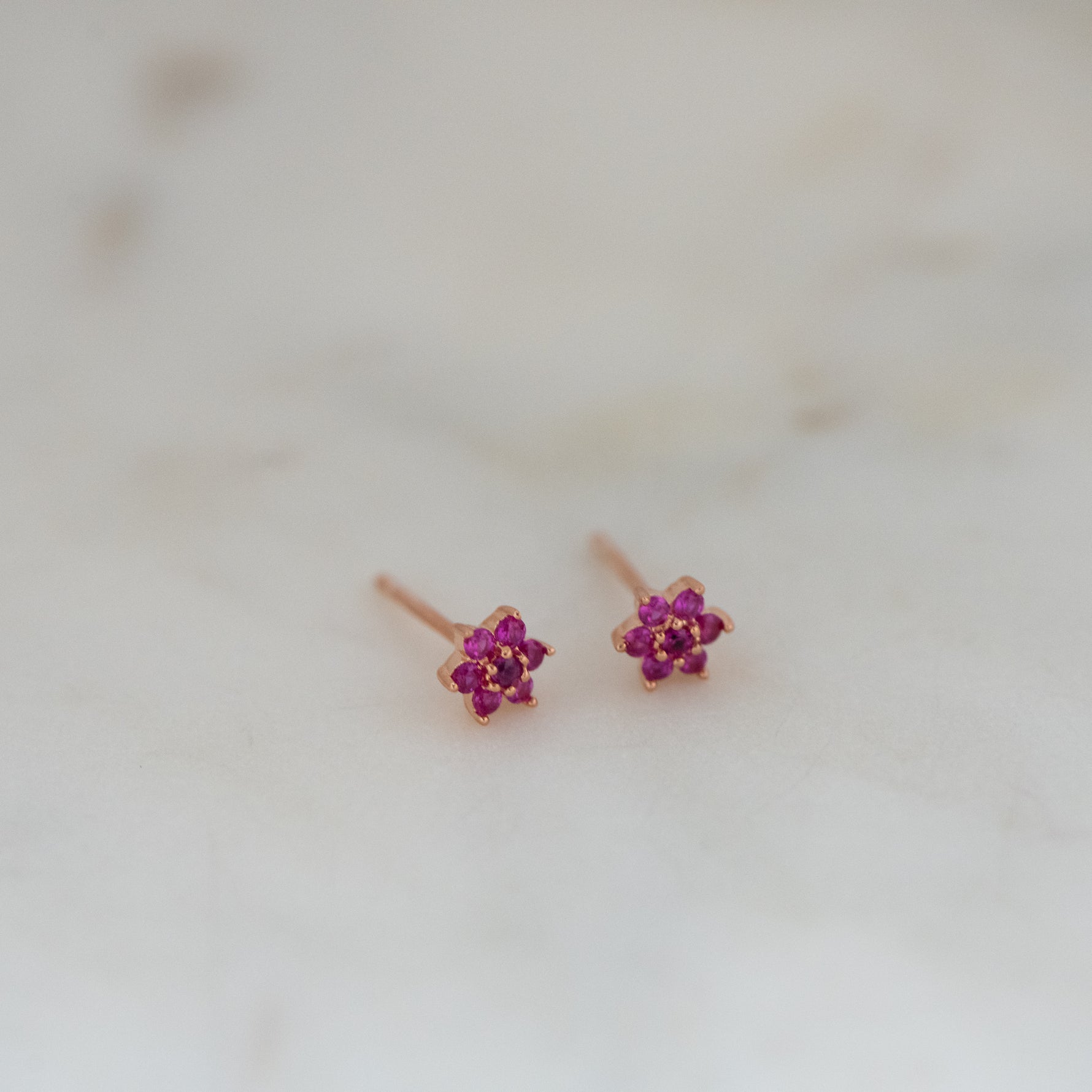Upclose shot of ruby rosegold floral stud earrings. 