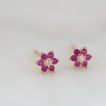 Upclose image of ruby flower stud earrings with diamond center. 