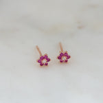Upclose image of rose gold ruby birthstone flower stud earrings.