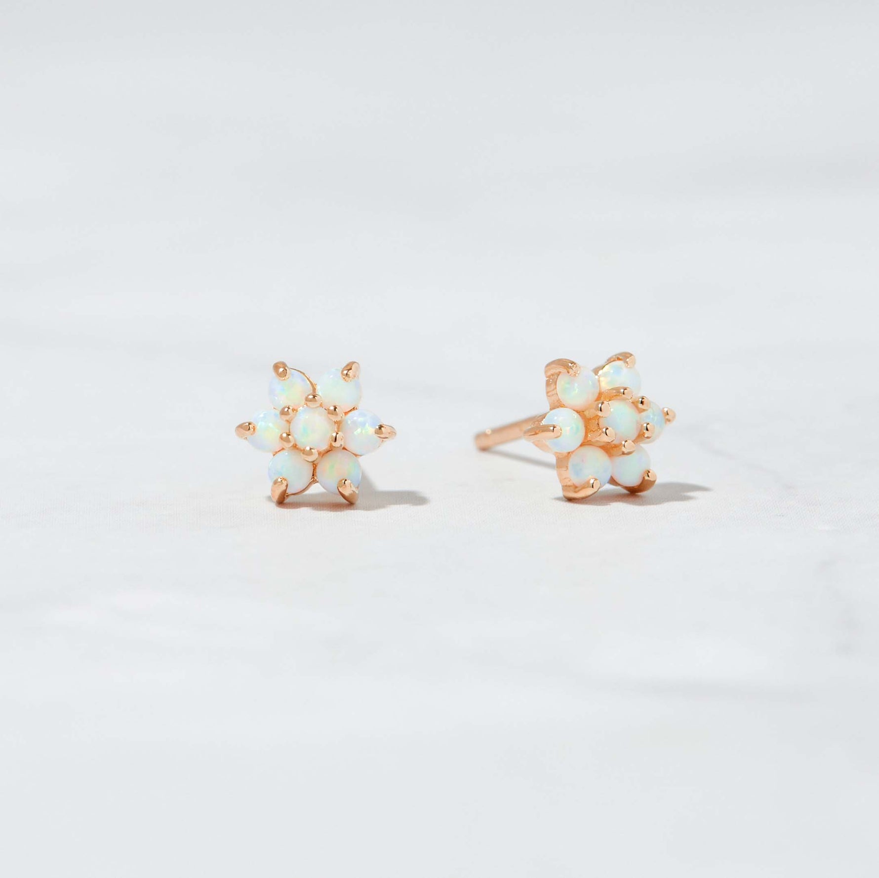 Rose gold October birthstone stud earrings with flower design.