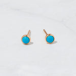 Rose gold turquoise stud earrings on marble background.