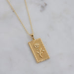 Up-close of gold rectangular medallion with 3D rose.
