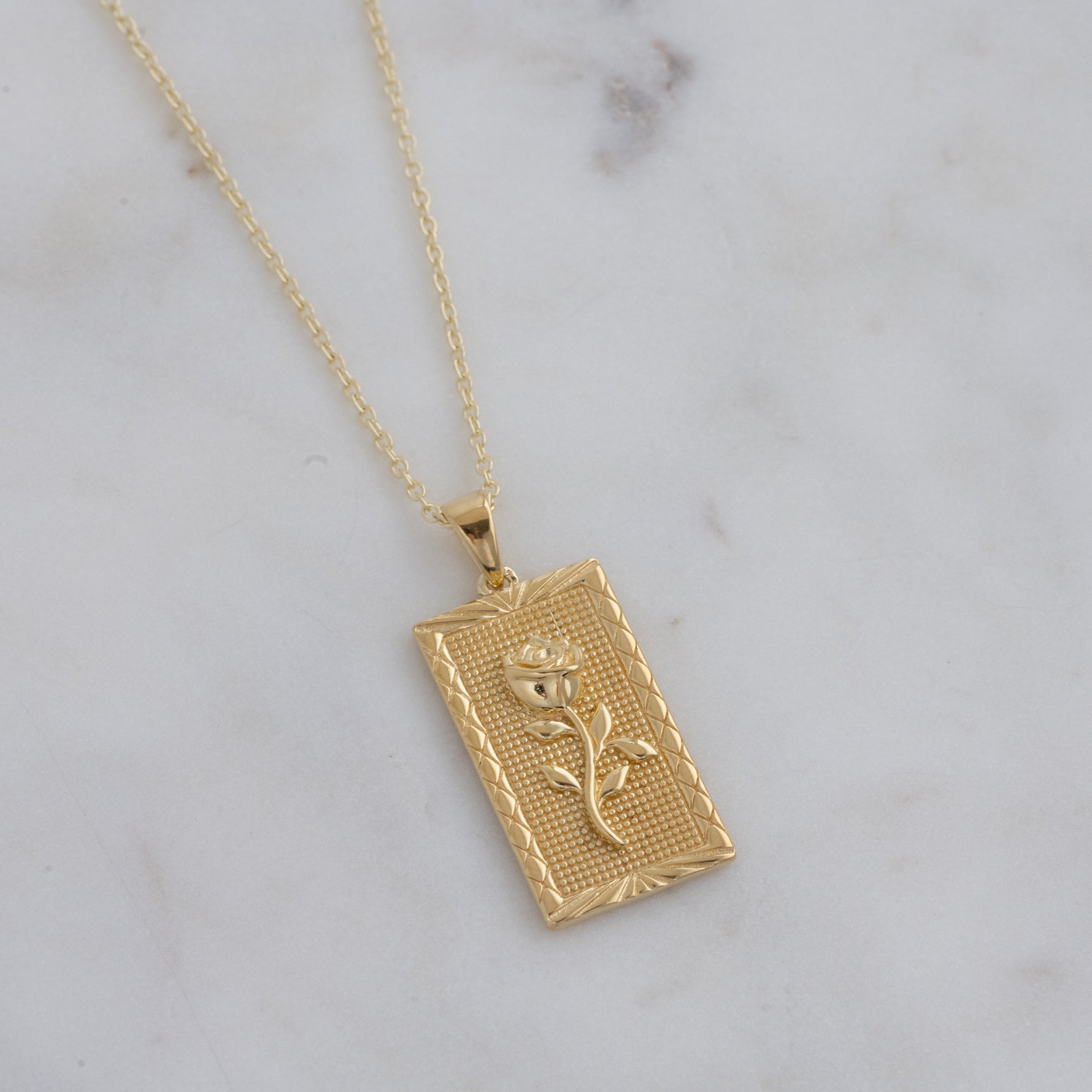 Up-close of gold rectangular medallion with 3D rose.