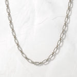 Trendy silver chain link statement necklace on marble background.