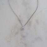Dainty silver round bezel pendant necklace on marble background