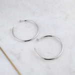 Large sterling silver lightweight hoop earrings on marble background.