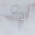 Delicate sterling silver spike charm huggie earrings on marble background