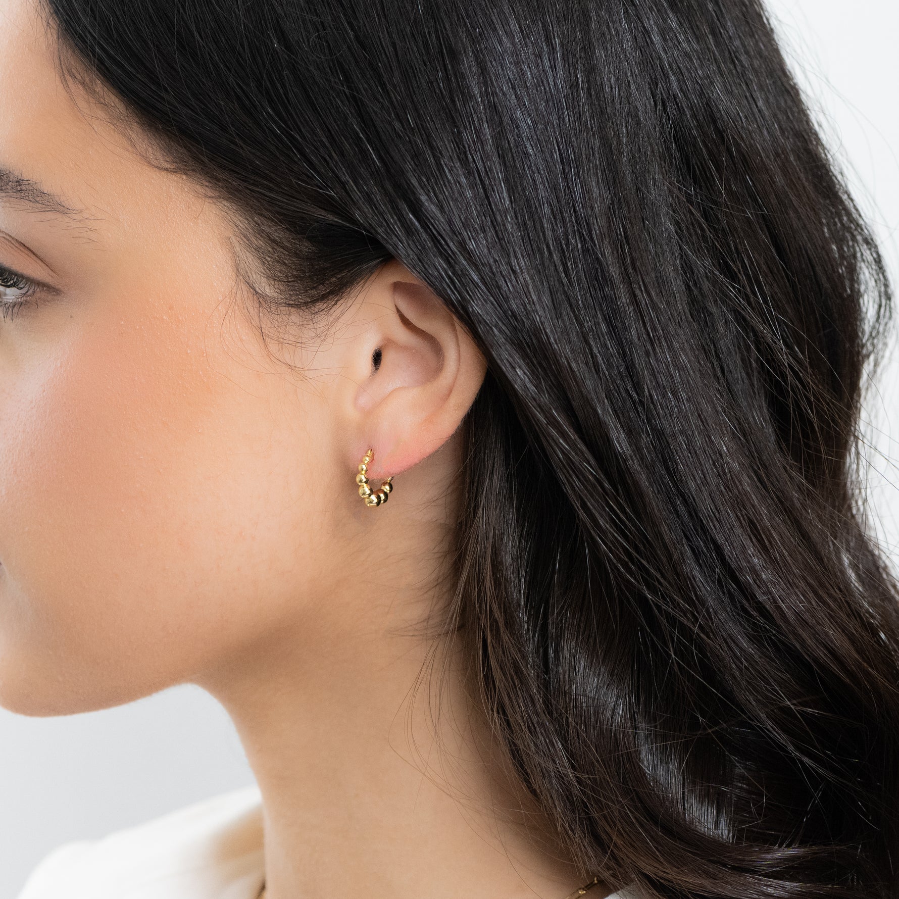 Model wearing beaded gold hoops 