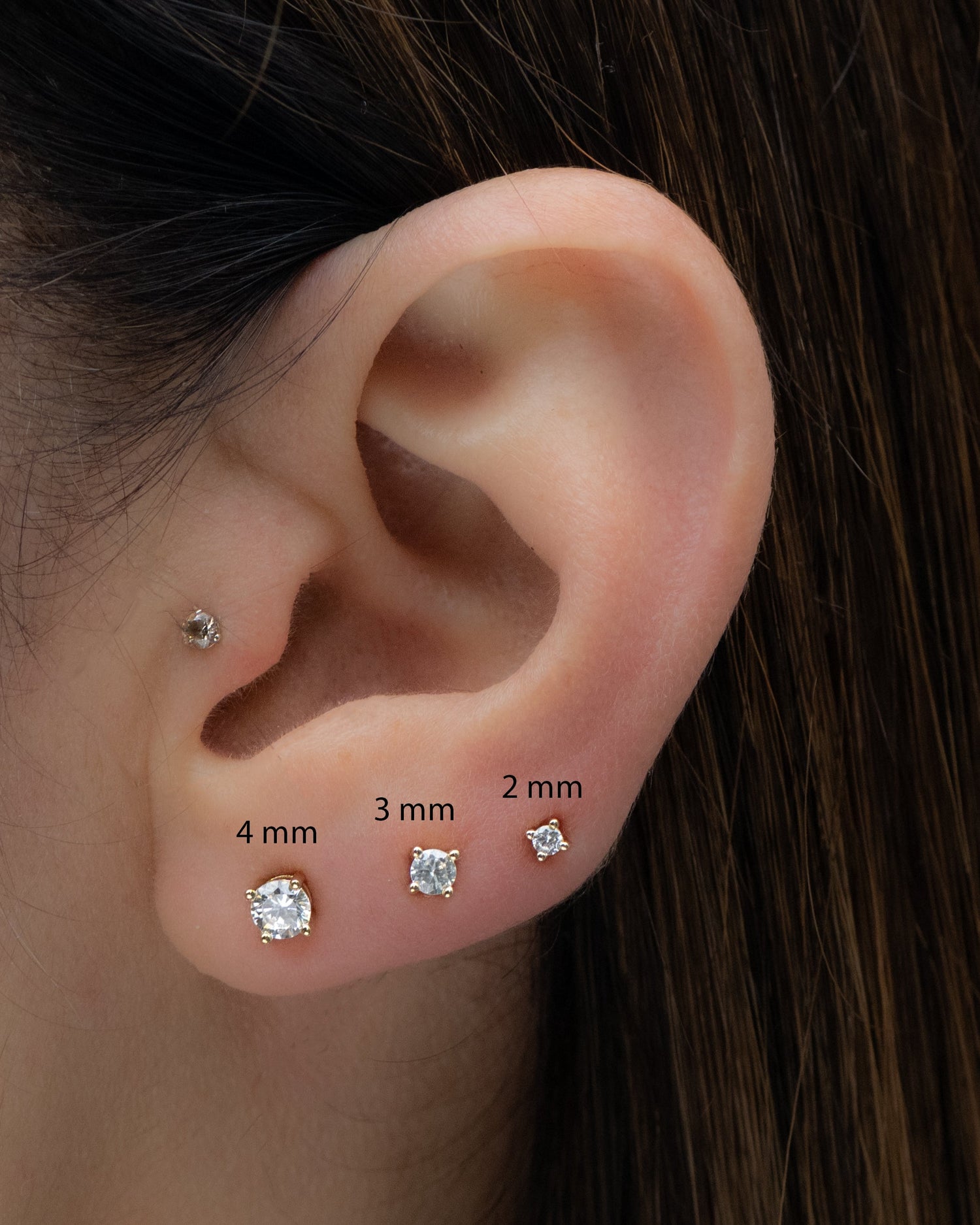Multiple sizes of diamond cz stud earrings shown on models ear, 4mm, 3mm and 2mm sizes