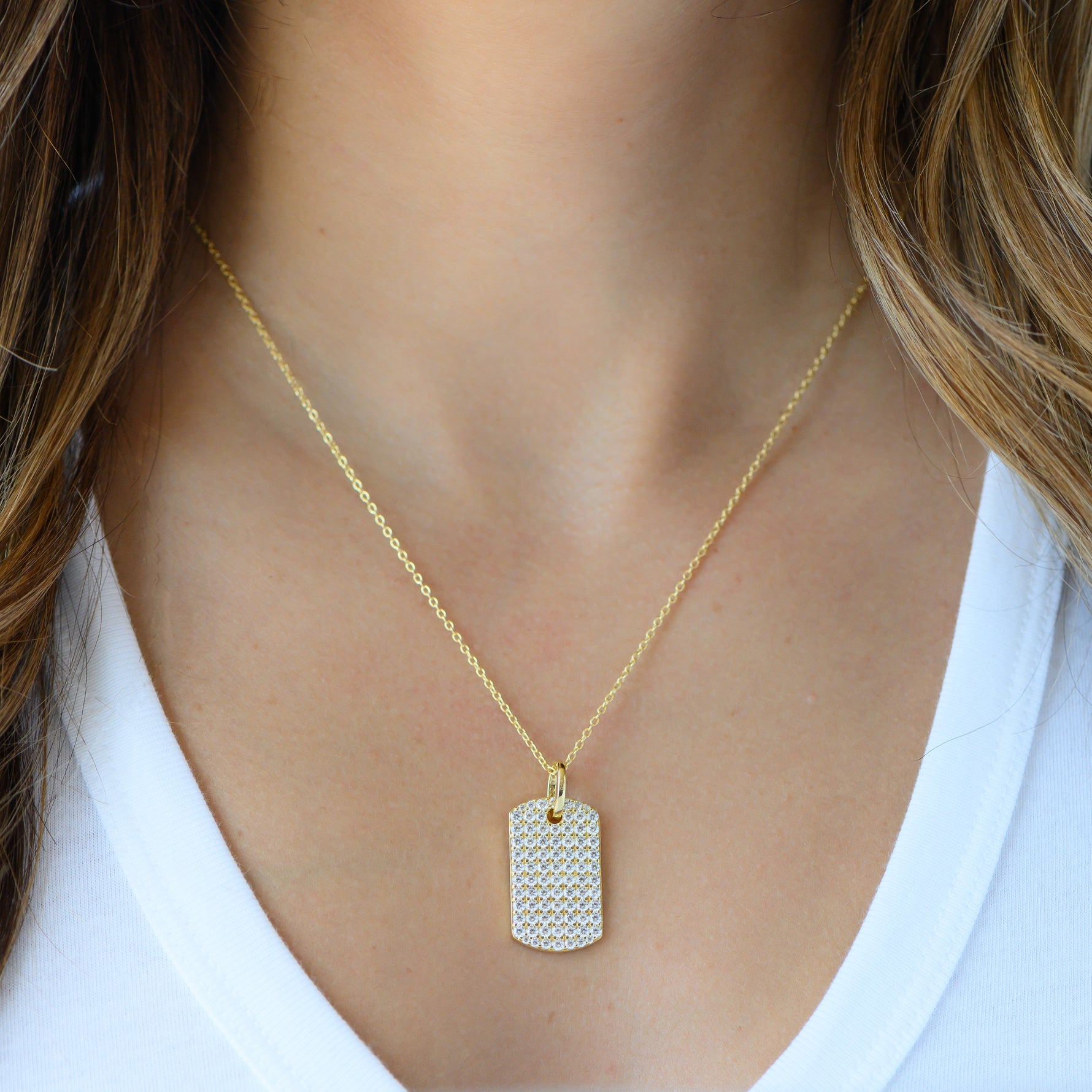 Model wearing gold pavé cz dog tag pendant necklace.