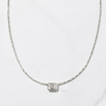 Silver baguette bezel pendant necklace on marble background
