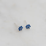 Upclose shot of sterling silver sapphire flower stud earrings.