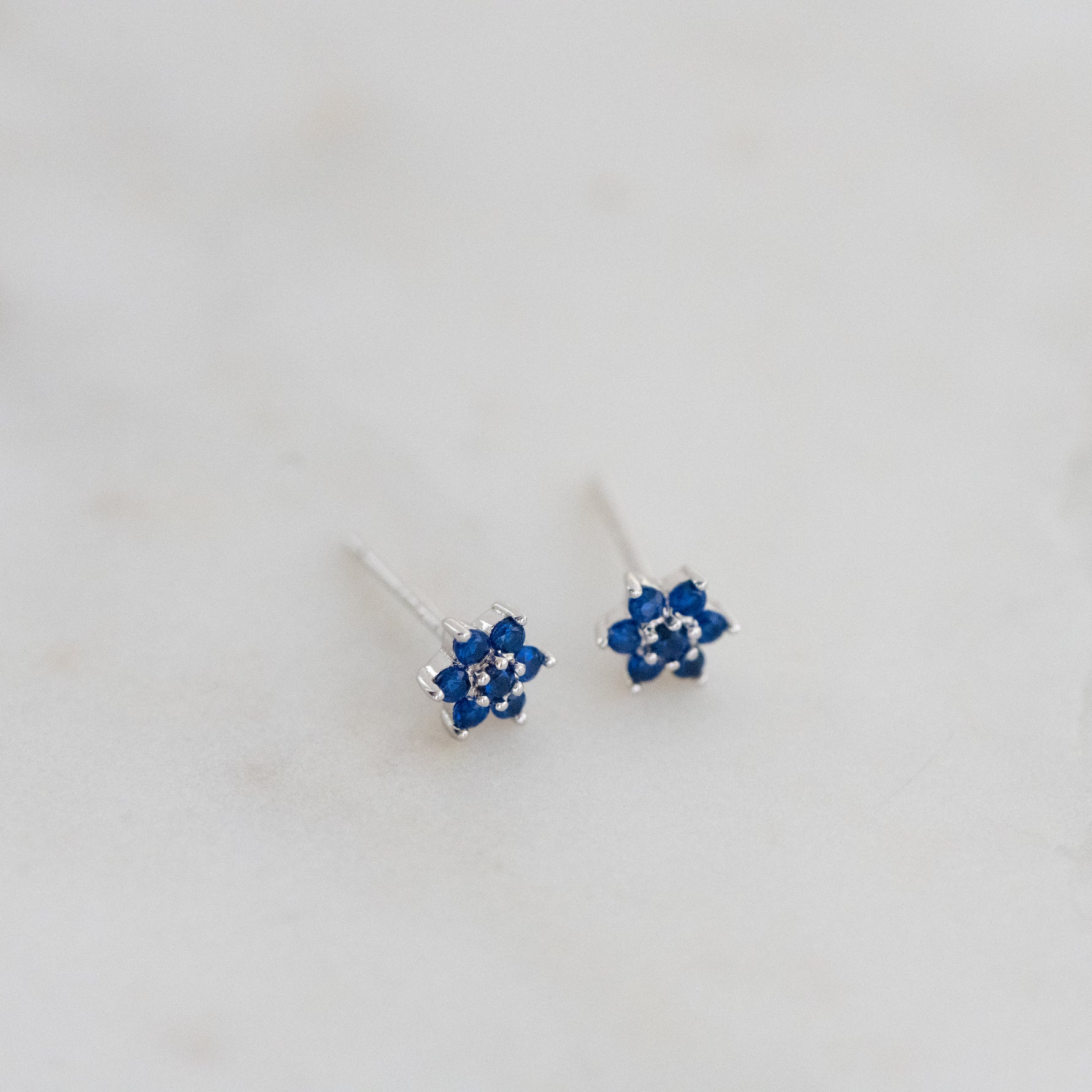 Upclose shot of sterling silver sapphire flower stud earrings.