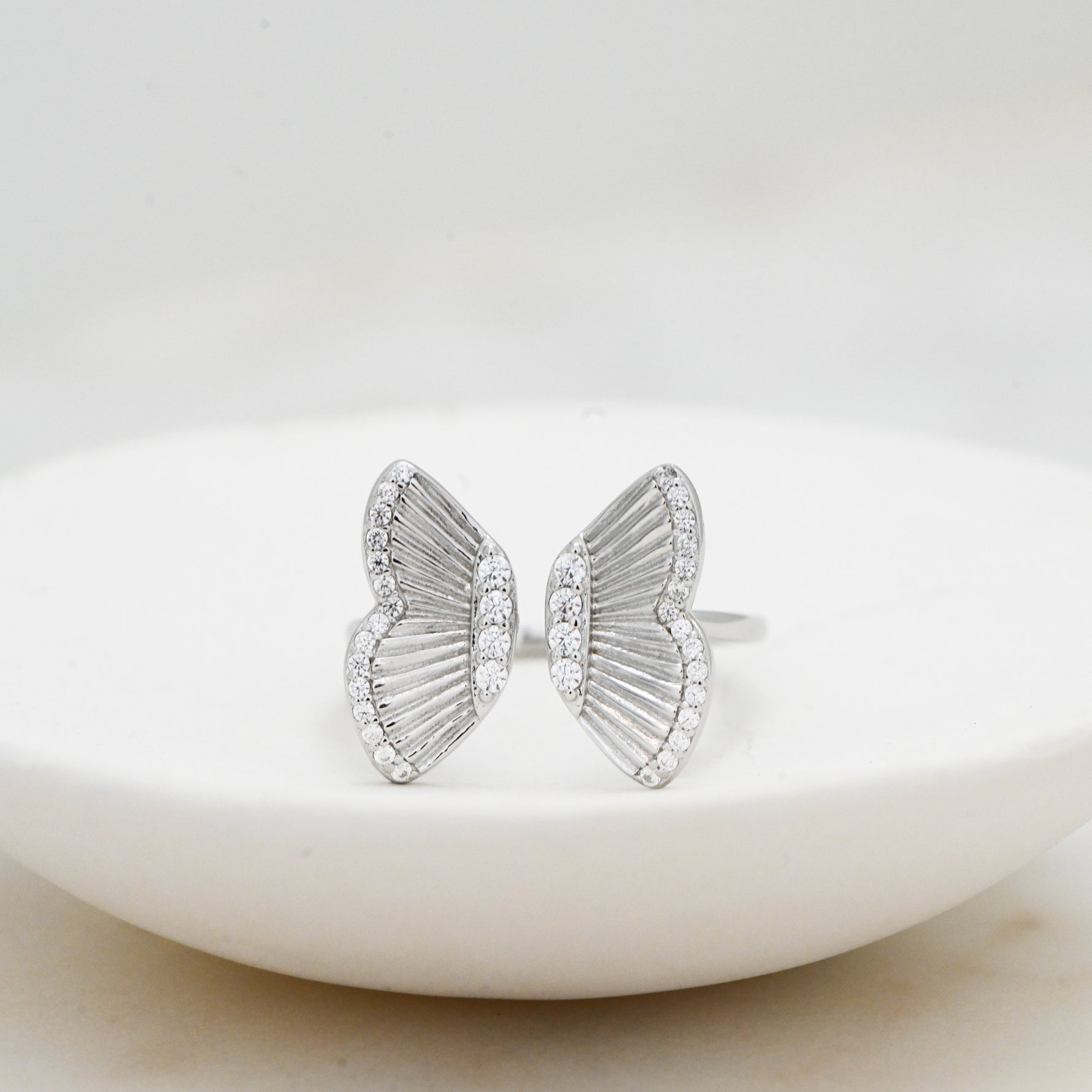 Delicate statement silver butterfly ring on a white plate. 