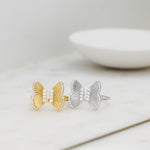 Gold and silver large butterfly adjustable rings on a marble background. 