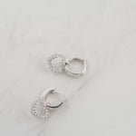 Silver dainty heart charm huggie hoop earrings upclose.