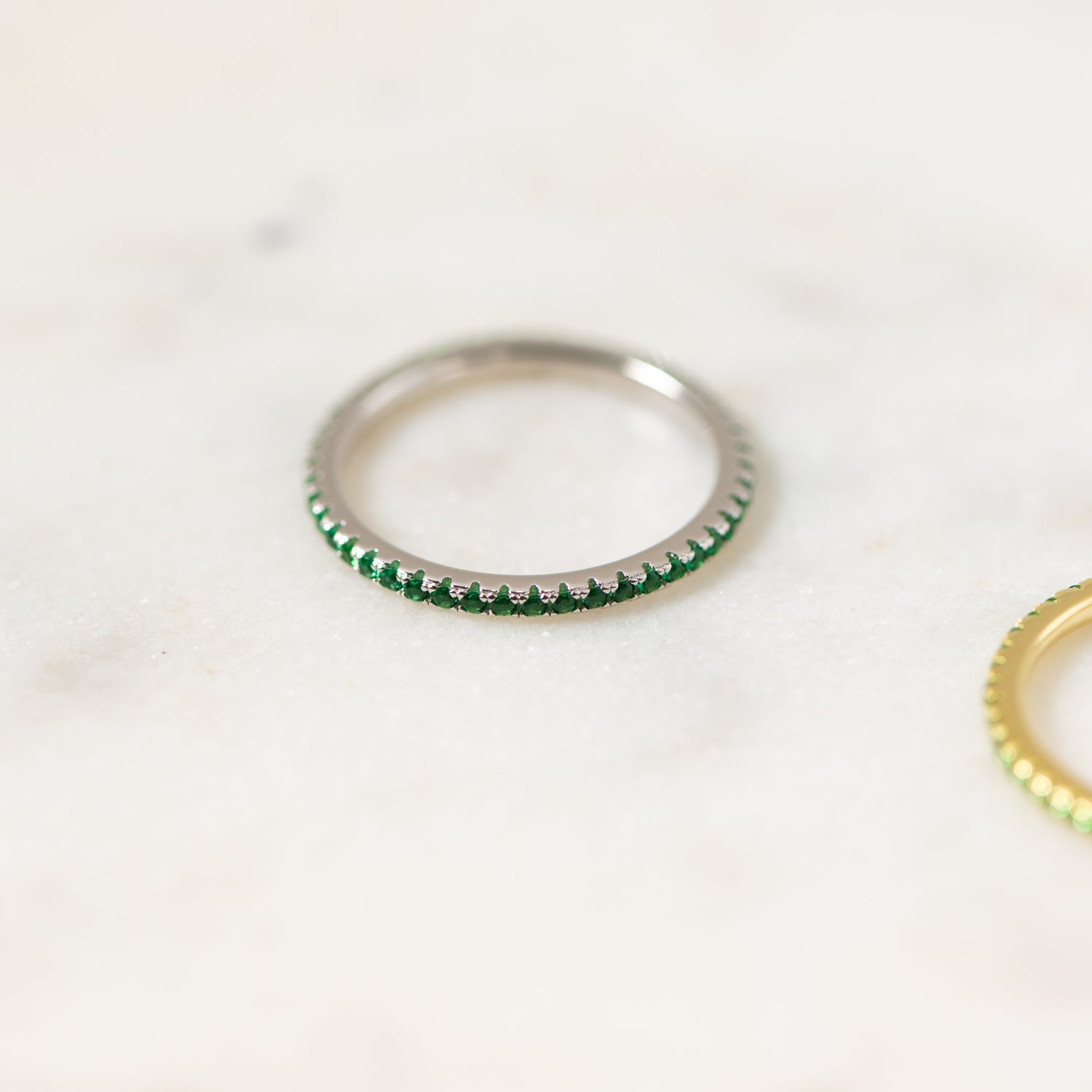 Delicate silver cz eternity birthstone ring in soft studio lighting.
