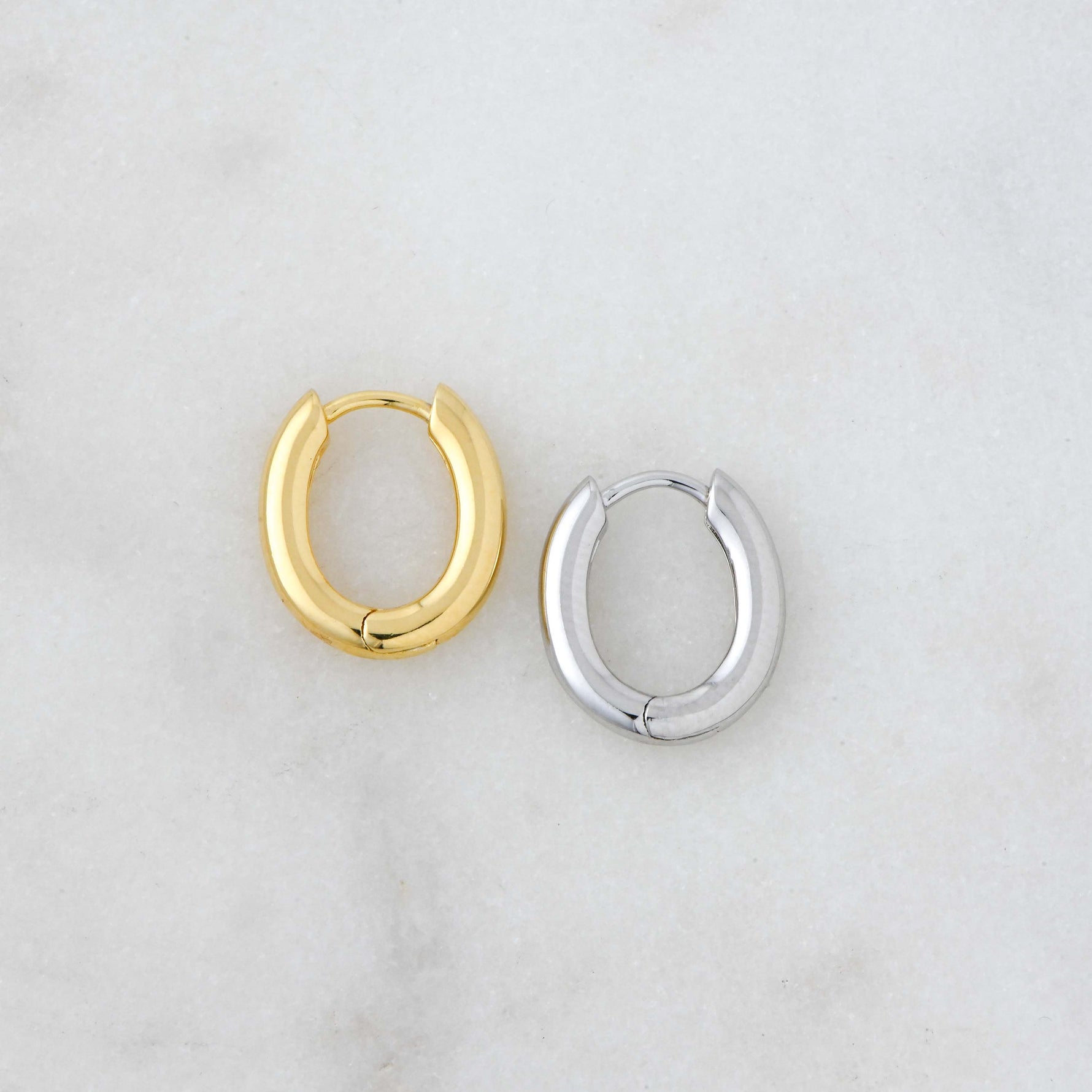 Gold and silver huggie hoop earrings side by side.