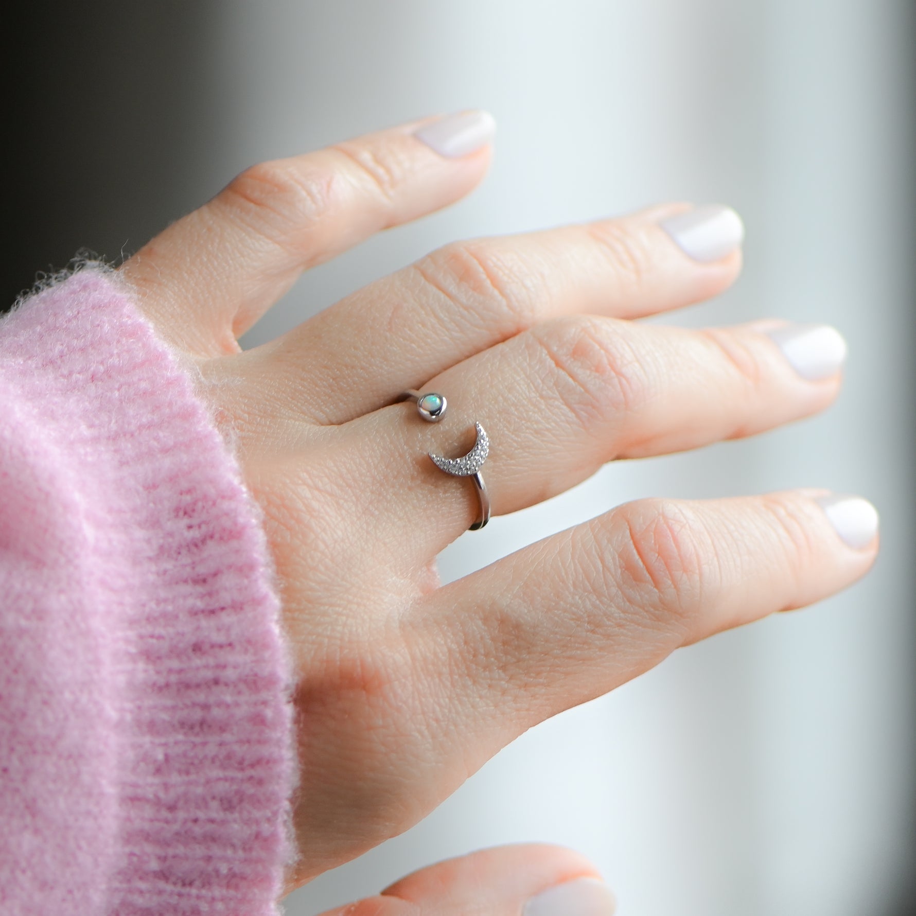 Model wearing opal and cz silver moon ring with adjustable band. 