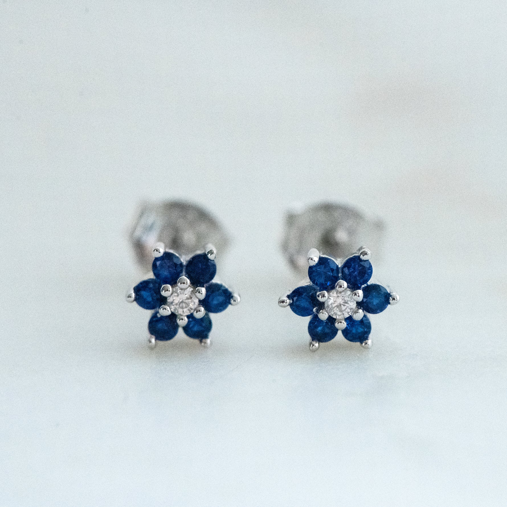 Upclose shot of sterling silver flower stud earrings with sapphire birthstone.
