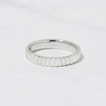Sterling silver textured ridged stacking ring on marble background. 