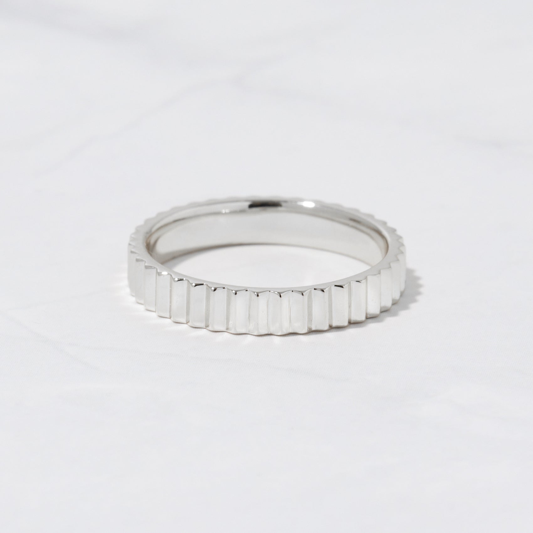 Sterling silver textured ridged stacking ring on marble background. 
