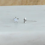 Up-close shot of delicate sterling silver plain star stud earrings. 