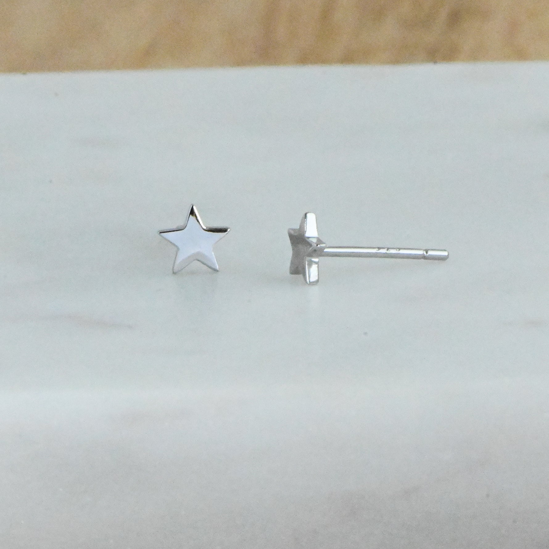 Up-close shot of delicate sterling silver plain star stud earrings. 