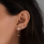 Model wearing gold minimalist stud earrings including a cluster diamond stud, an opal stud, and a ball stud. 